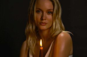 Zara Larssoon sitter med ett brinnande ljus i ena handen.